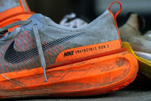 Close-up of worn Nike Invincible Run 3 shoes on concrete, showing wear and tear.